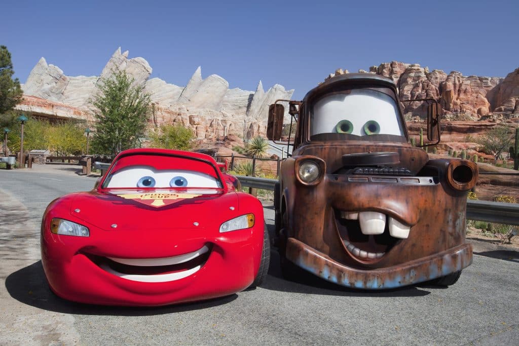 Rayo McQueen y Mate posando en Cars Land con las montañas desérticas de Radiator Springs de fondo