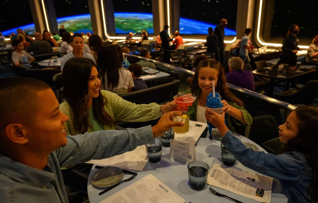 cuánto cuesta comer en disney depende del restaurante. Foto de una familia comiendo en el restaurante Space 220 de Epcot, que simula ser un viaje al espacio