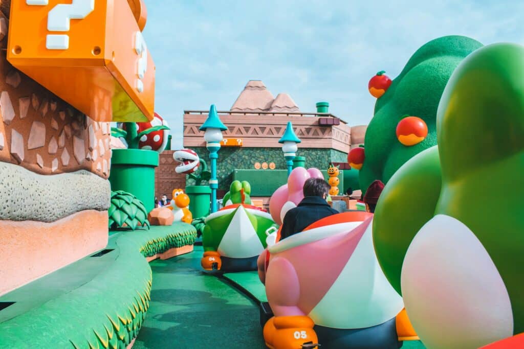 A bordo de la atracción de Yoshi en Universal Studios Japan. Vista trasera de un vehículo con forma de Yoshi rosa y otro Yoshi verde recorriendo el mundo de Nintendo. Es uno de los destinos de Universal Studios en el mundo