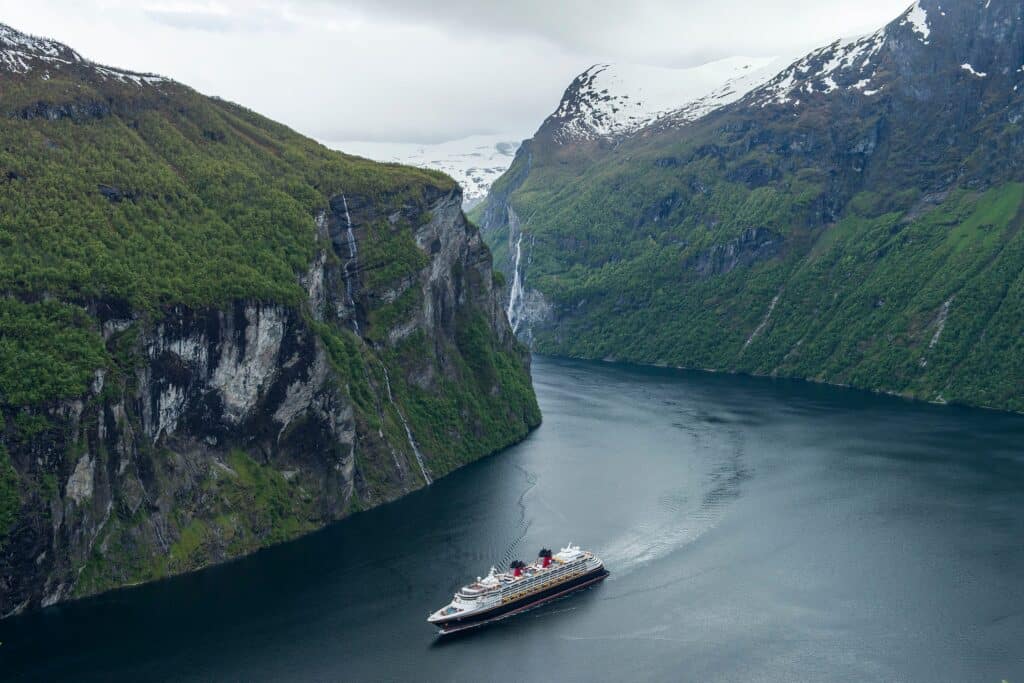 Vista aérea de un crucero de Disney atravesando la naturaleza de Noruega. Este es uno de los itinerarios extraordinarios de Disney Cruise Line más demandados.